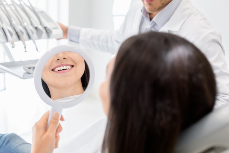 happy-female-patient-looking-at-mirror-in-dental