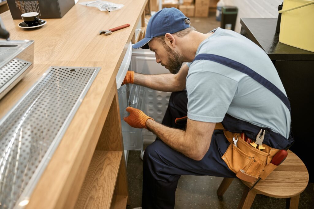 bearded-young-man-repairing-fridge-in-cafe-2022-02-16-18-45-38-utc-min-1024×683